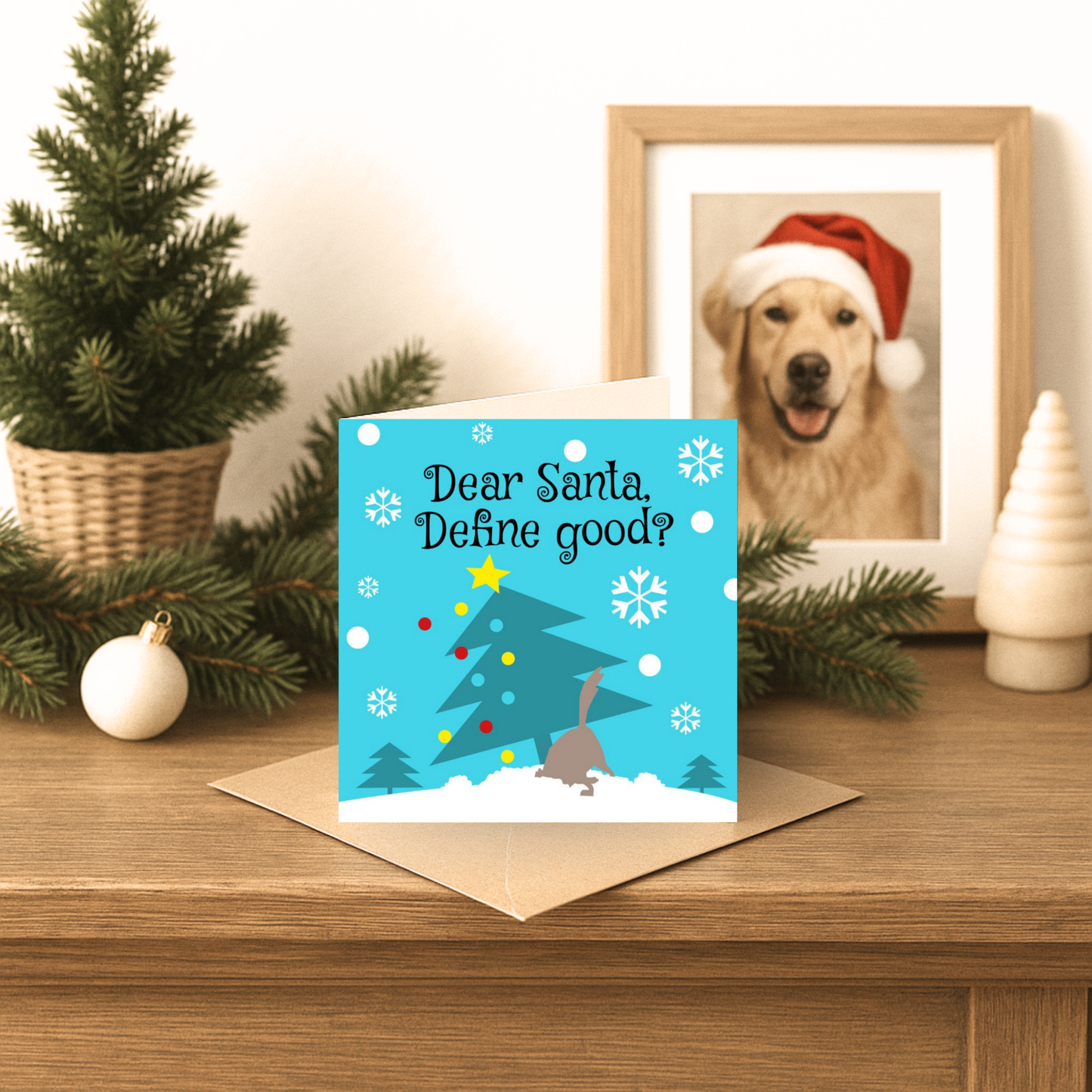 Christmas card with a tree and reindeer design on a wooden surface with festive decorations.