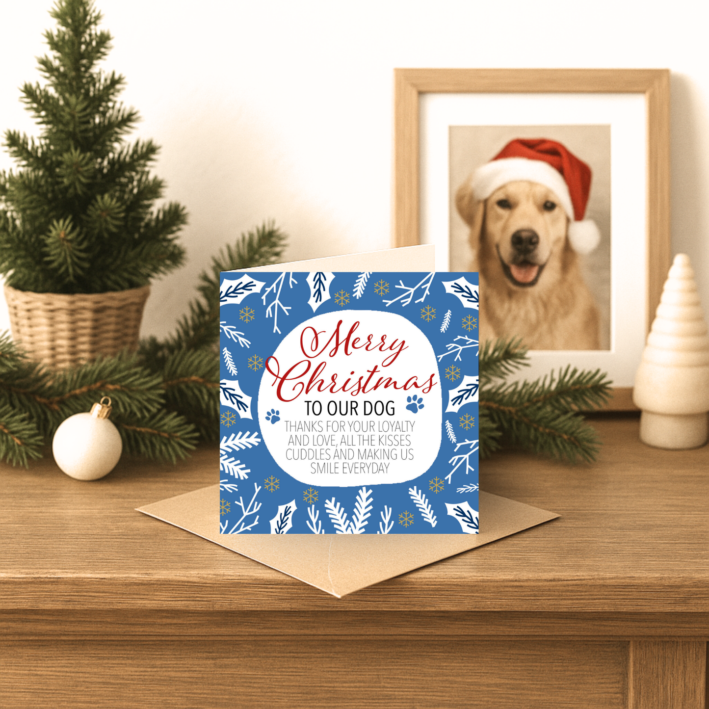 Christmas card for dogs with a blue border on a wooden surface with festive decorations.
