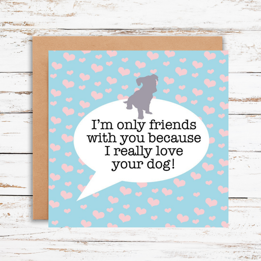 Card with dog silhouette and text on a blue background with pink hearts, placed on a wooden surface.