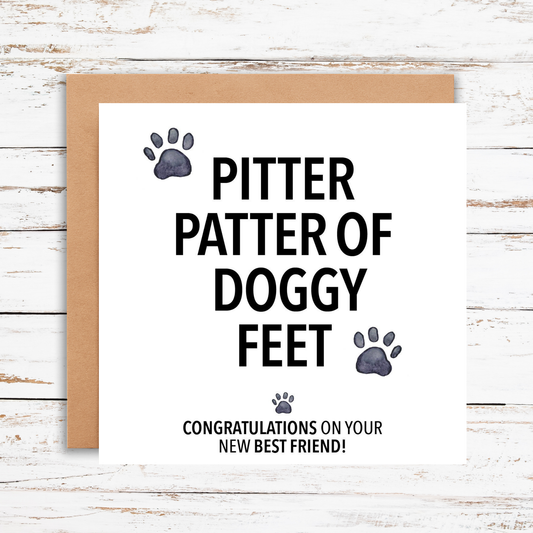 Greeting card with 'Pitter patter of doggy feet' text and paw prints on a wooden surface