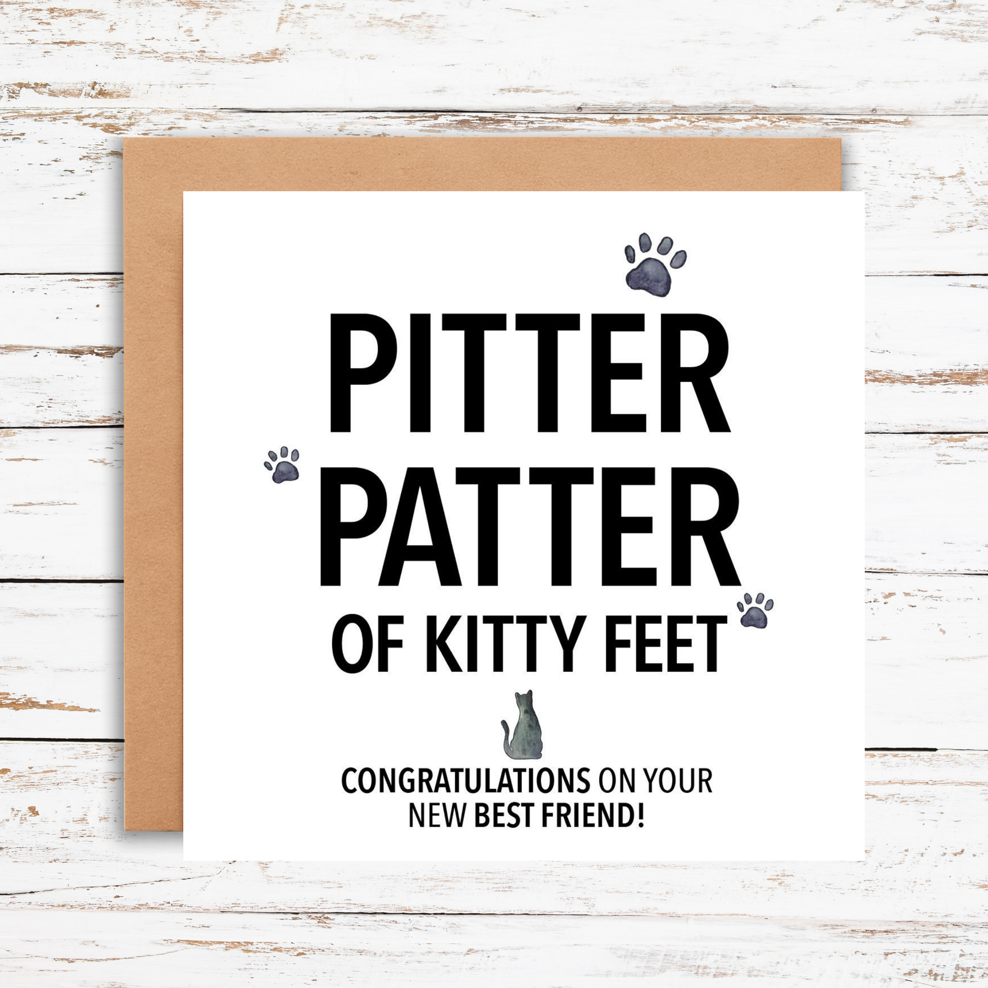 Greeting card with 'Pitter patter of kitty feet' text on a wooden surface