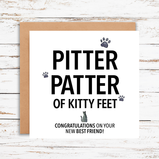 Greeting card with 'Pitter patter of kitty feet' text on a wooden surface