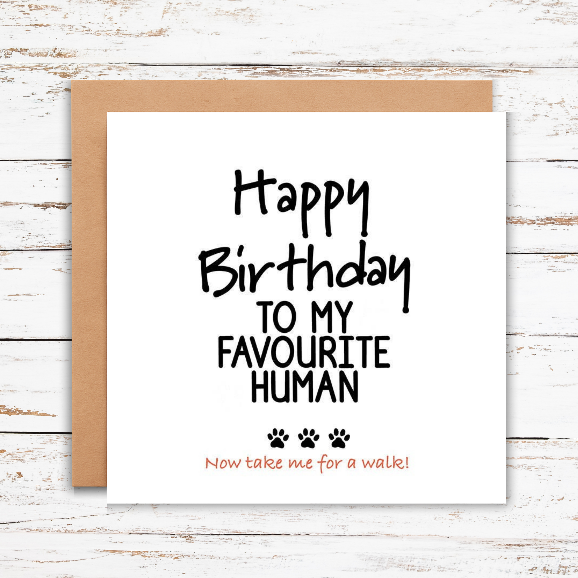 Birthday card with text 'Happy Birthday to my favourite human Now take me for a walk!' on a wooden surface.