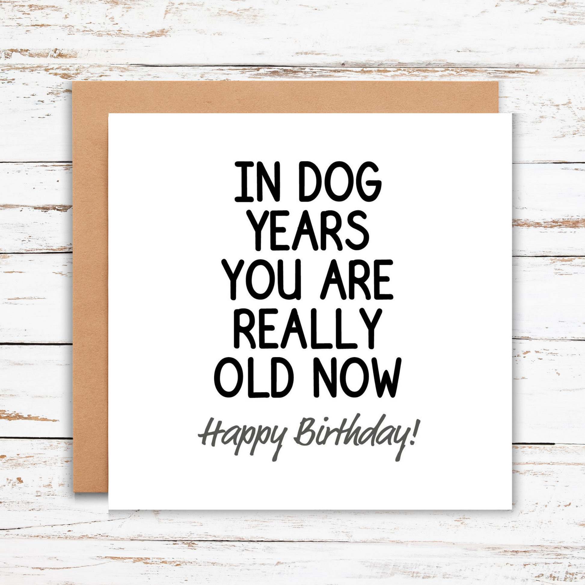 Birthday card with humorous text on a wooden surface