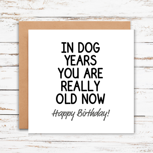 Birthday card with humorous text on a wooden surface