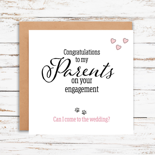 Greeting card with text 'Congratulations to my Parents on your engagement. Can I come to the wedding?' on a wooden surface.