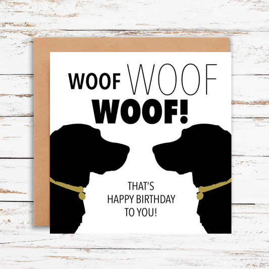Birthday card with dog silhouettes and 'Woof Woof' text on a wooden surface