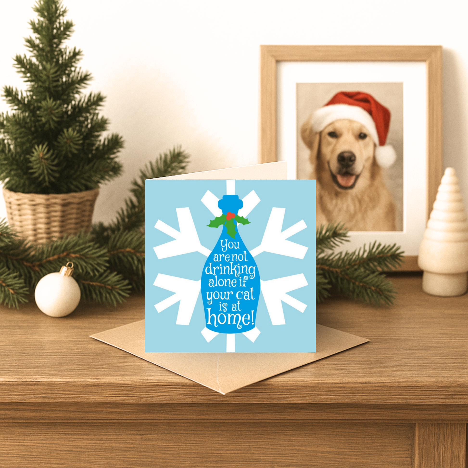 Card with snowflake design and humorous text on a table with Christmas decorations.