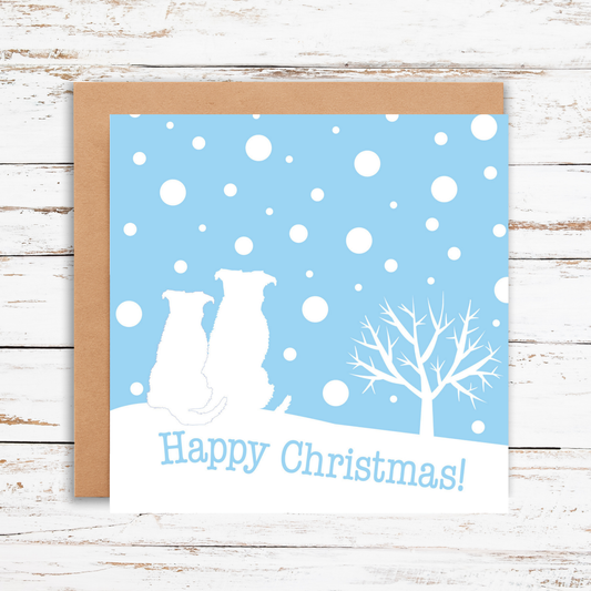 Christmas card with two dogs and a tree on a blue snowy background