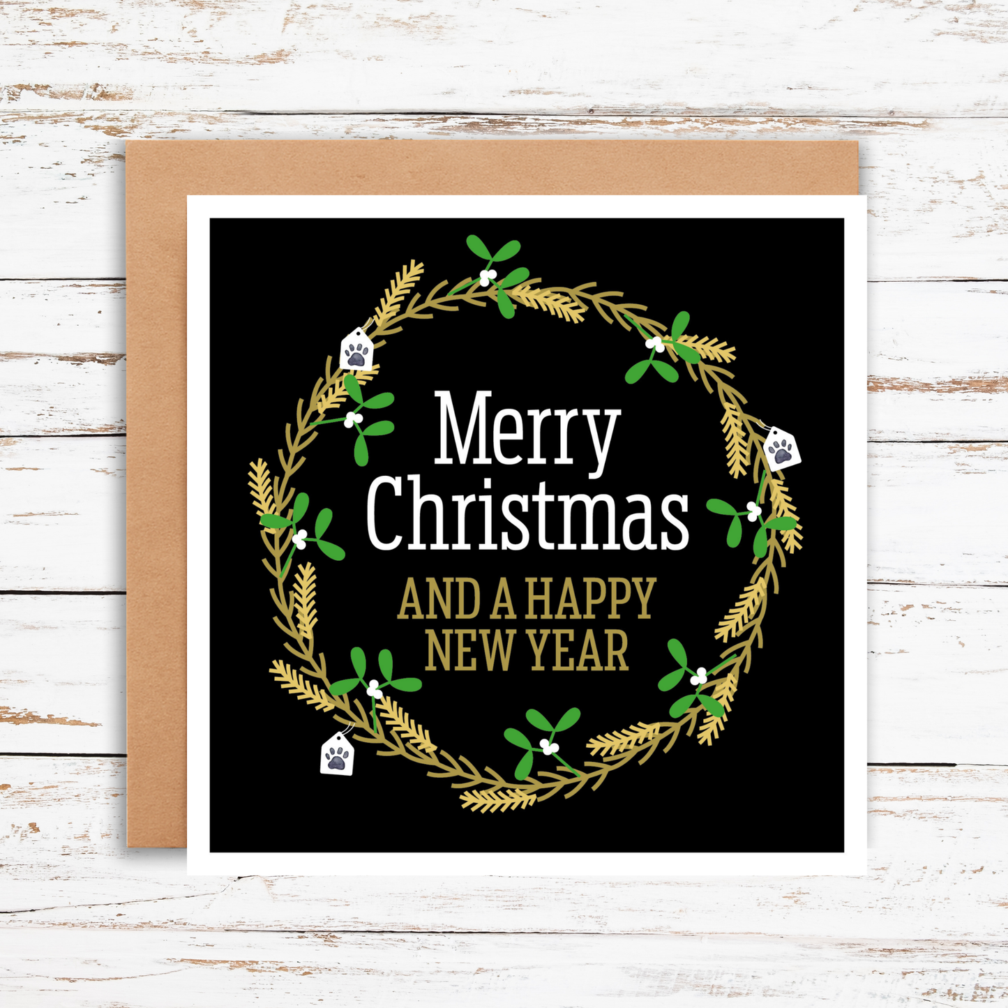 Christmas card with wreath design and text on a wooden surface