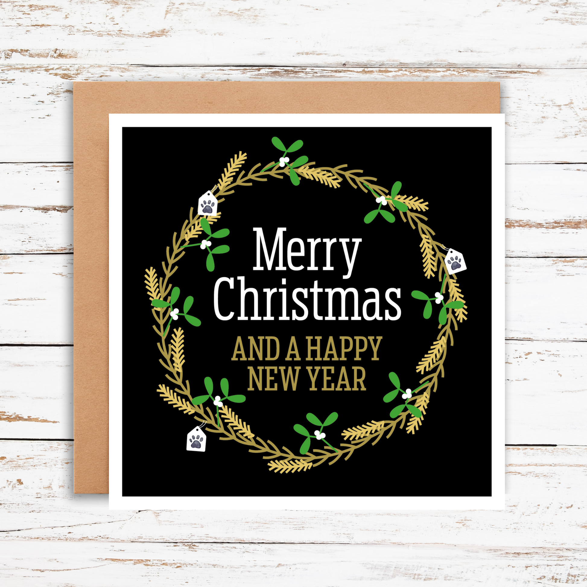 Christmas card with wreath design and text on a wooden surface