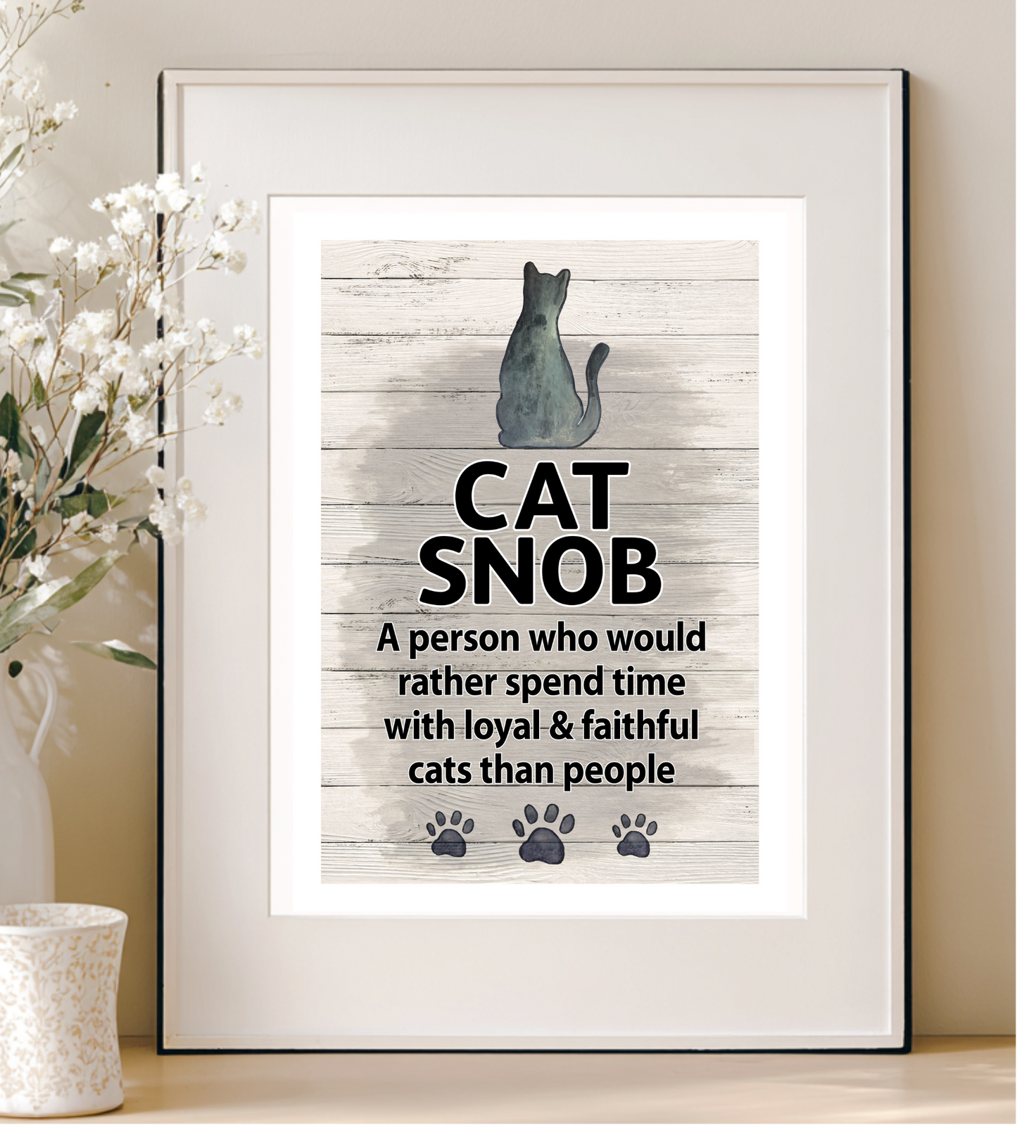 Framed print with a cat illustration and text on a wooden background