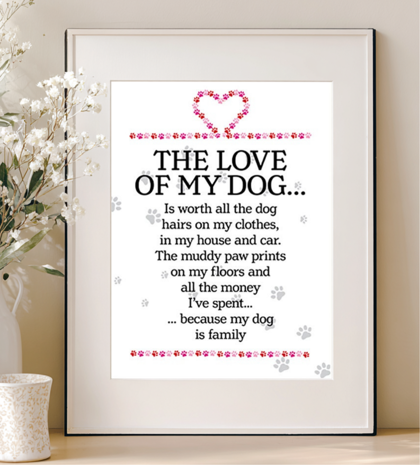 Framed print with a quote about the love of a dog, placed on a surface with decorative elements.