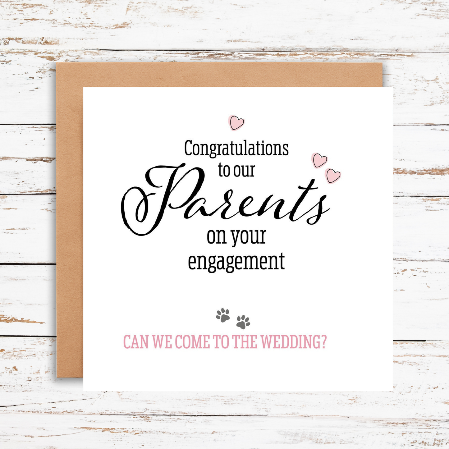 Greeting card with congratulations on engagement text and question about wedding invitation on a wooden surface.