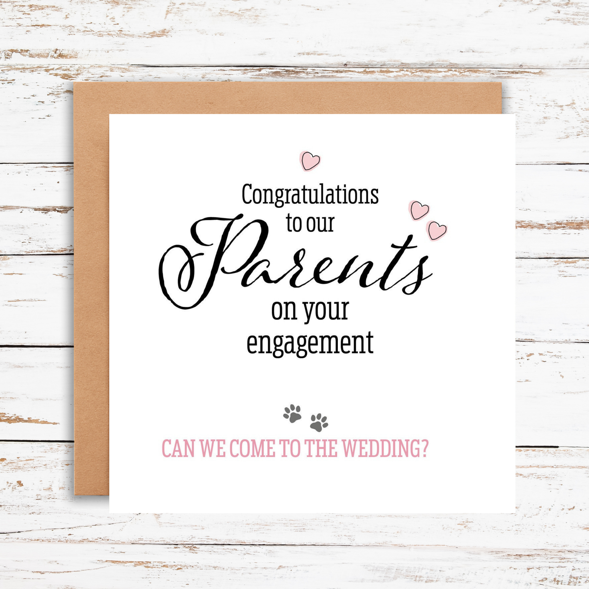 Greeting card with congratulations on engagement text and question about wedding invitation on a wooden surface.